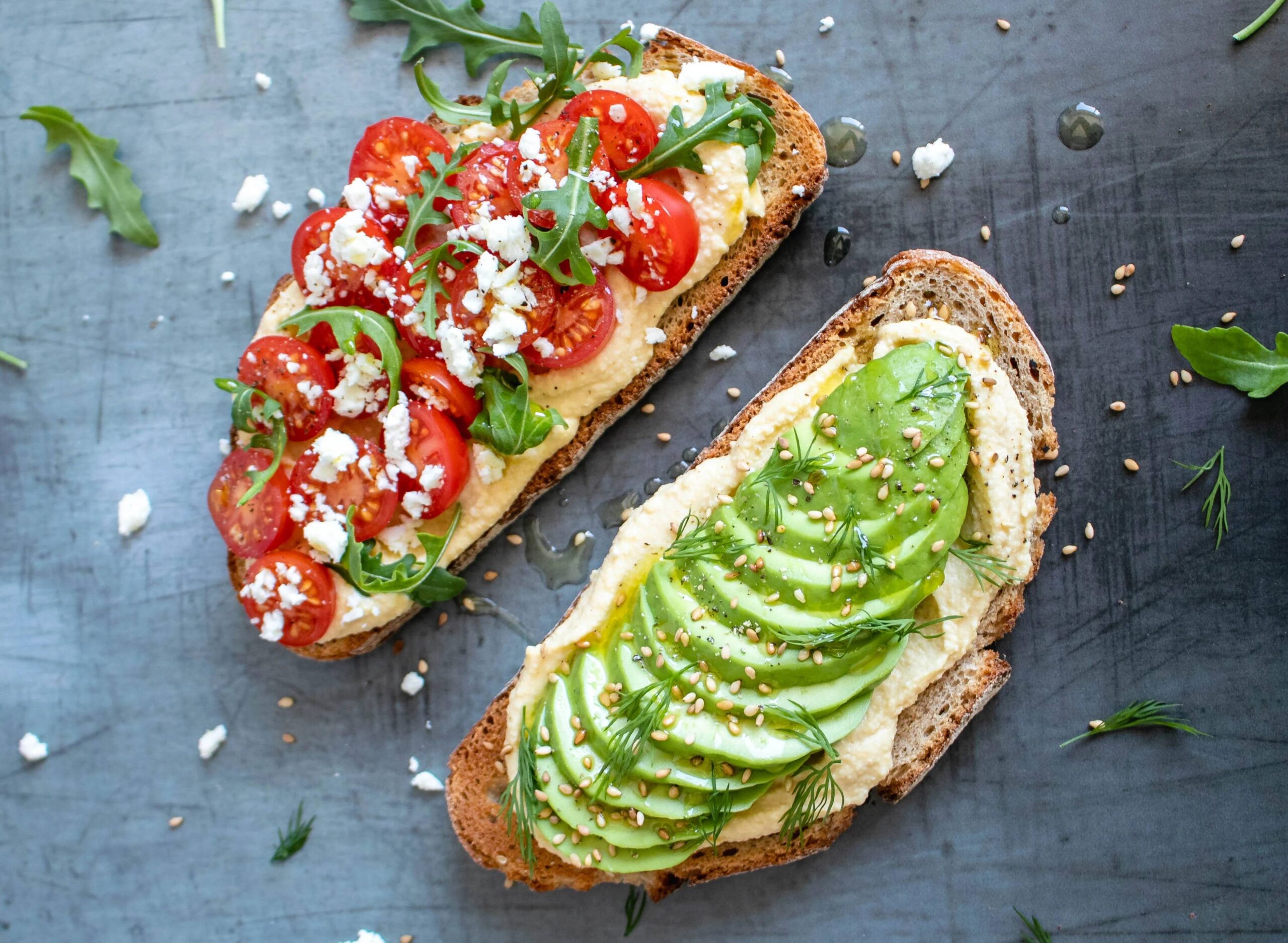 Vegan toast topped with hummus, avocado, and fresh vegetables
