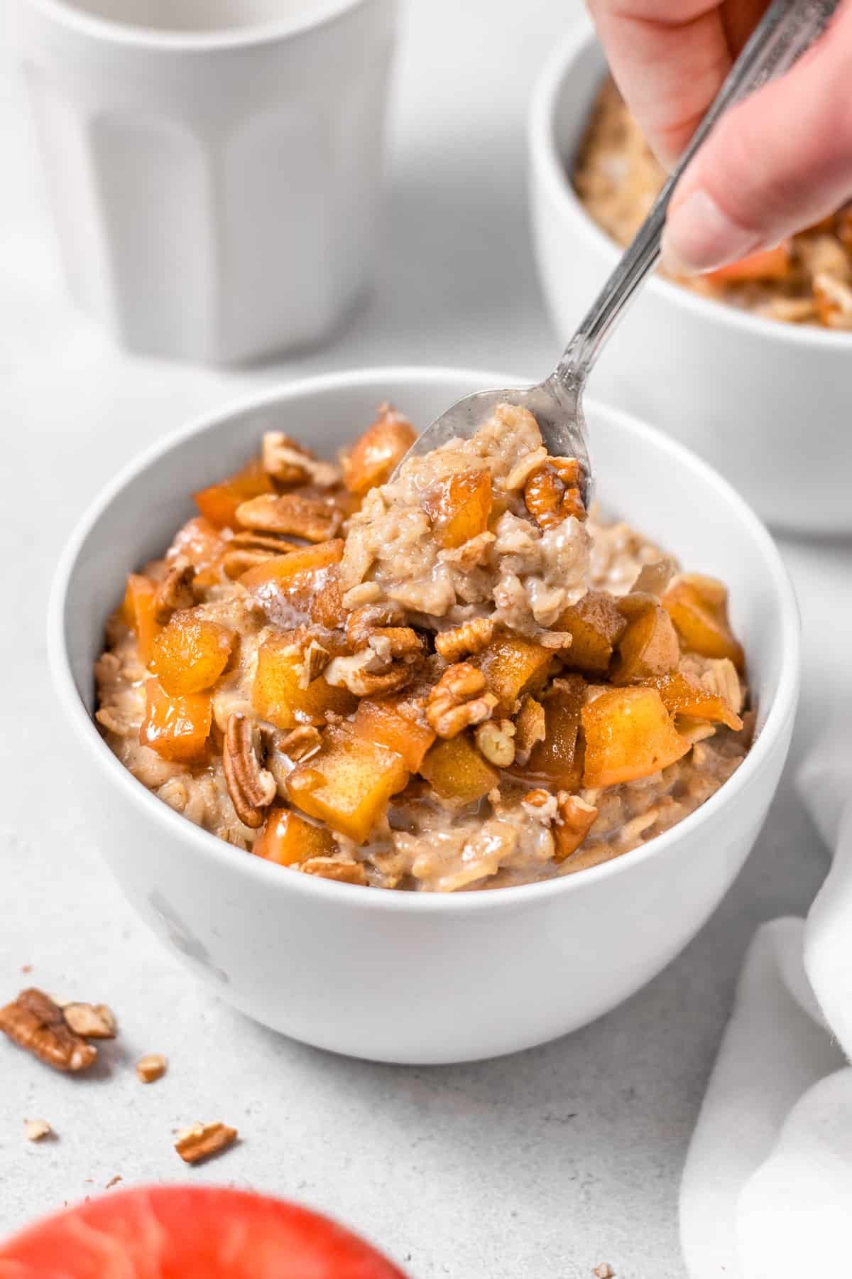 Bowl of vegan apple cinnamon oatmeal topped with cooked diced apples and fresh apple slices
