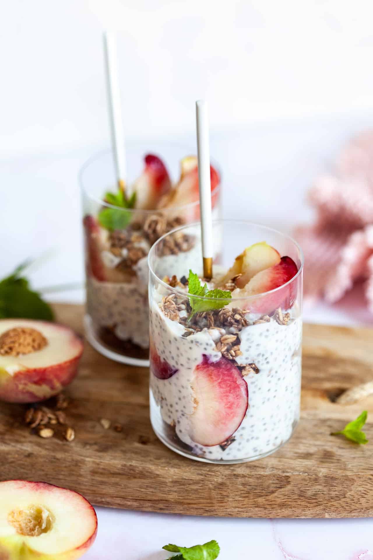 Glass jars of chia pudding layered with berries, kiwi, yoghurt, passion fruit, and mint