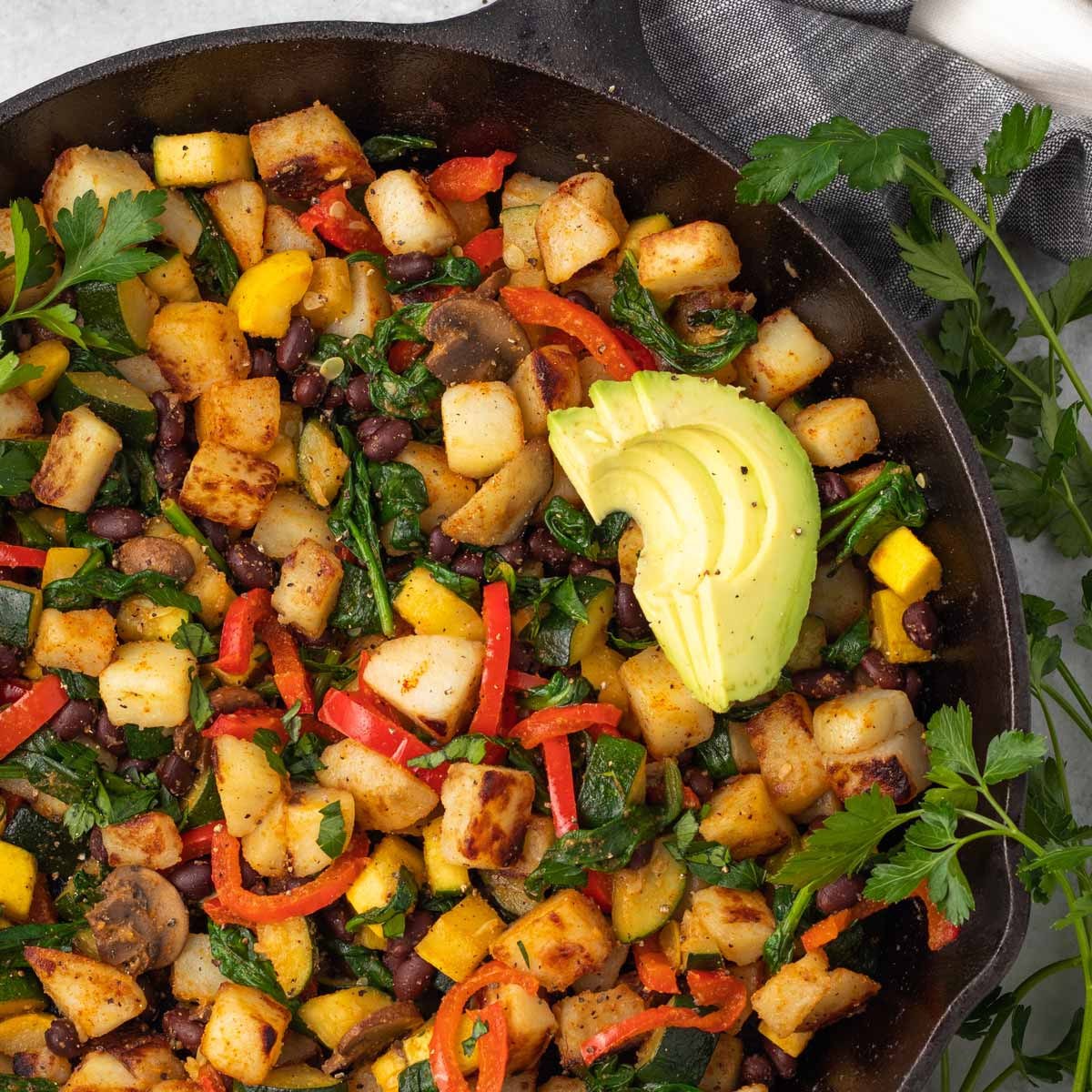Vegan breakfast hash made with potatoes, black beans, salsa, mashed avocado, and coriander