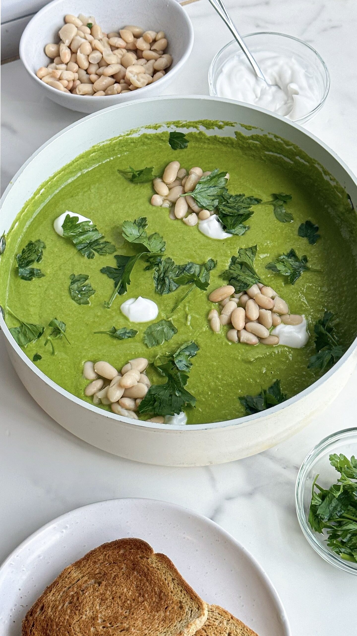 Bowl of vegan split pea and white bean soup with visible greens and vegetables