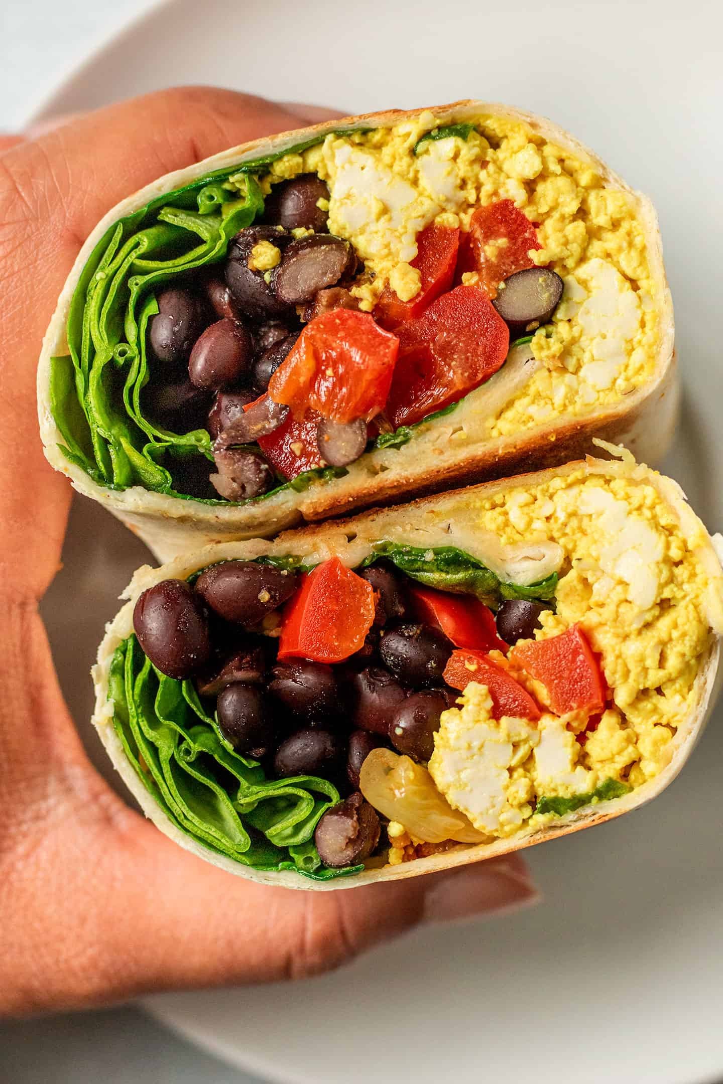 Tofu breakfast wraps filled with avocado, tomato, spinach, and vegan tofu scramble