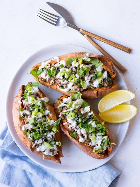 Baked sweet potatoes filled with lentils and topped with sauce and seeds