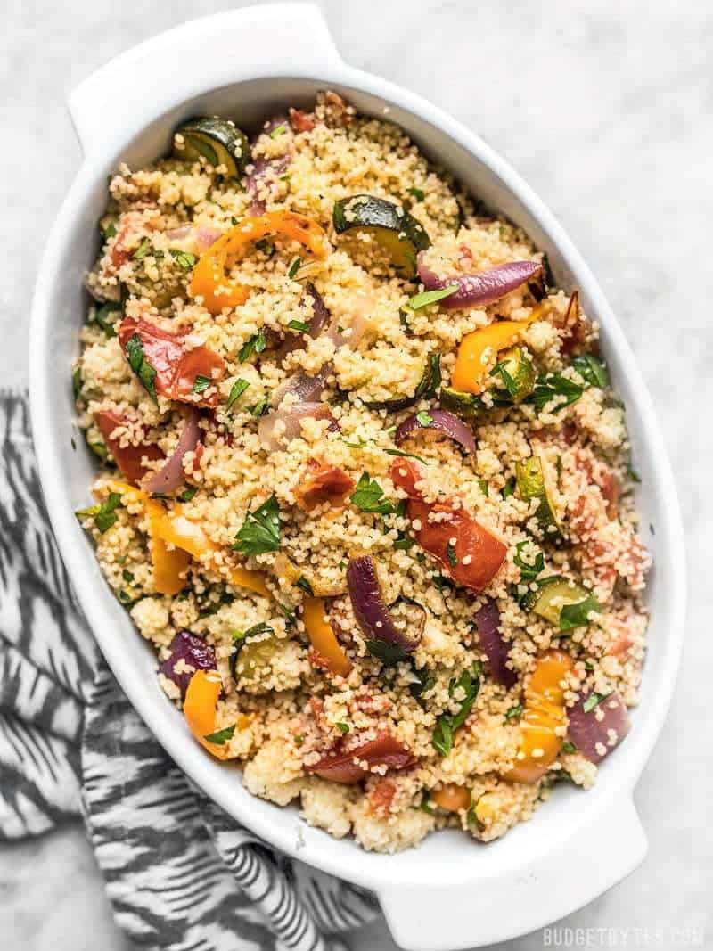 Harissa-roasted vegetable couscous bowl with charred zucchini, capsicum, cherry tomatoes and tahini drizzle