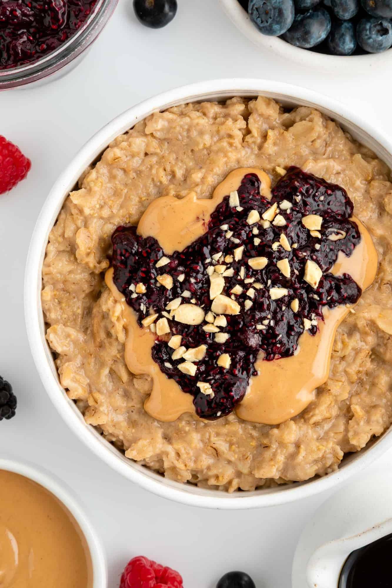 Bowl of peanut butter and jam oatmeal topped with berries and served with a spoon