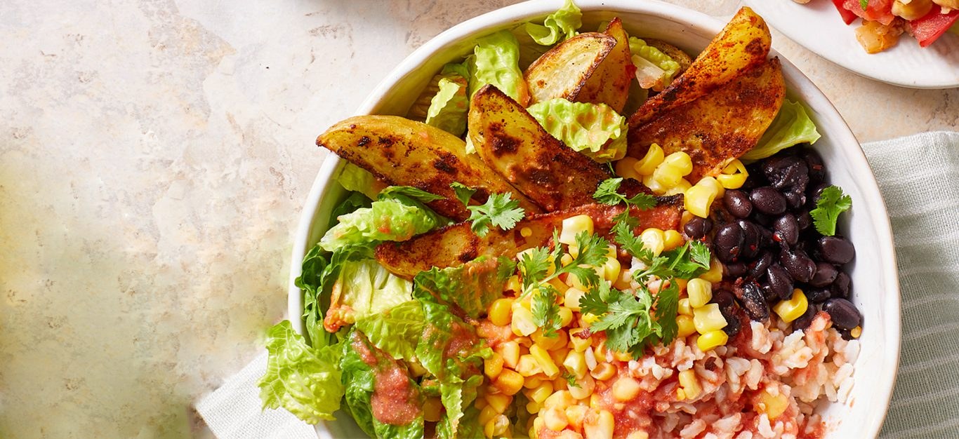 Vegan potato burrito bowl with crispy potato wedges, beans, rice and salsa fresca