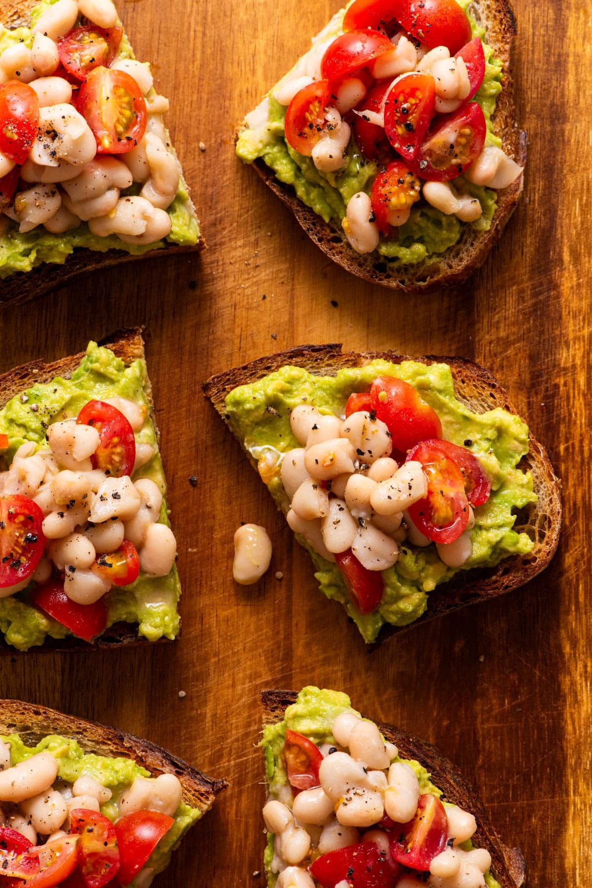 Toasted bread slices topped with mashed white beans, tomato, and basil