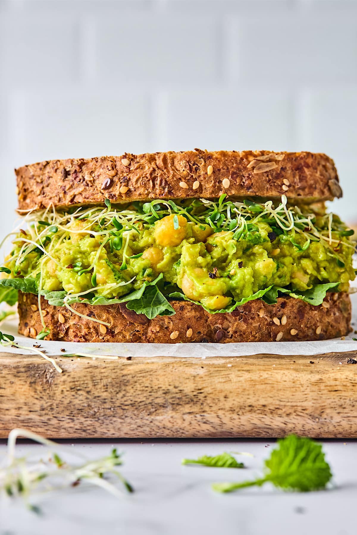 Open-faced toasted sandwich topped with creamy chickpea and avocado filling and fresh greens