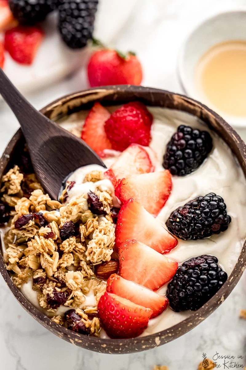 Colourful plant-based yoghurt breakfast bowl topped with fruit, nuts, and seeds