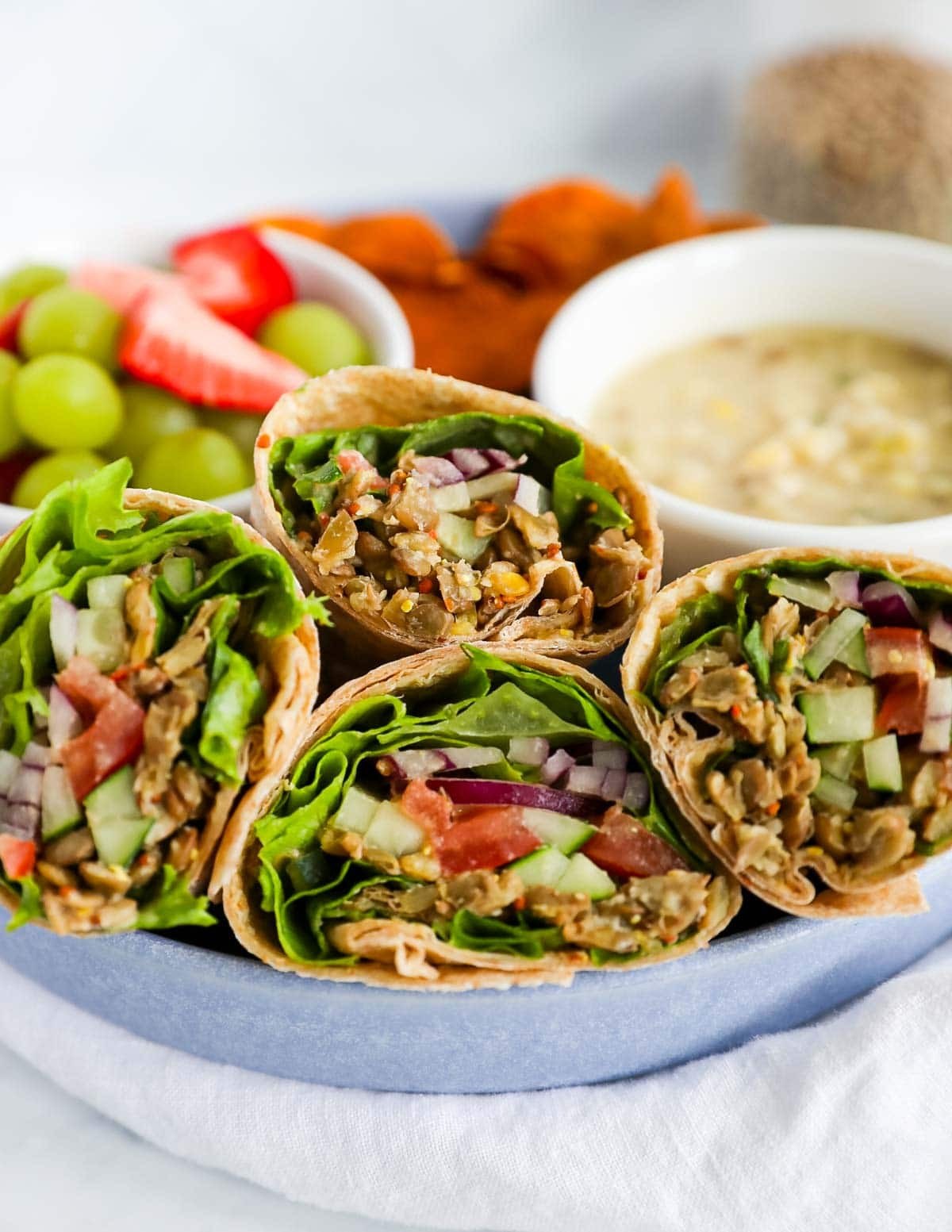 Vegan lentil and roasted vegetable wrap with hummus, greens and colourful vegetables